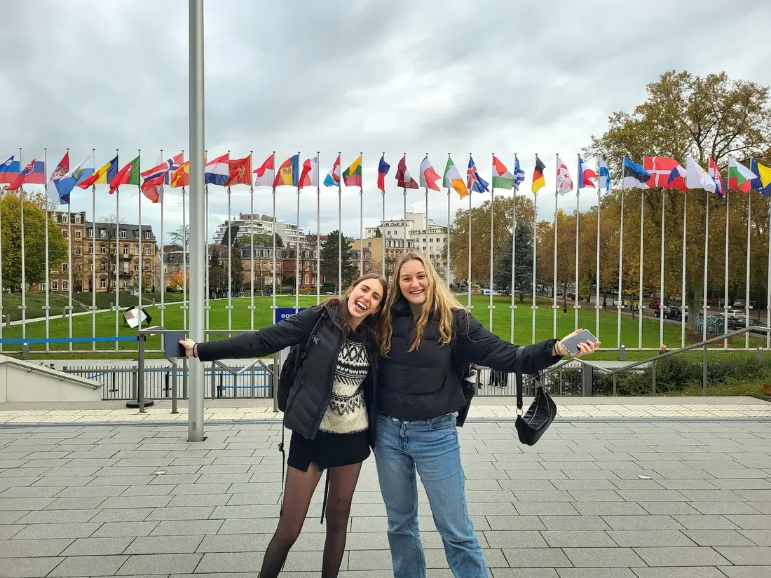 Students pose for picture in front of flags.